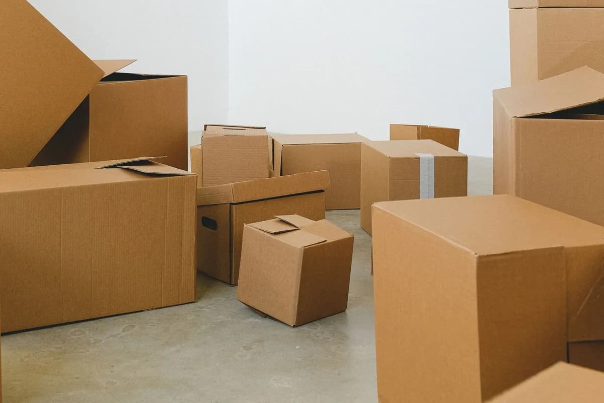 Opened and part-collapsed cardboard moving boxes standing on the bare floor of an empty room.