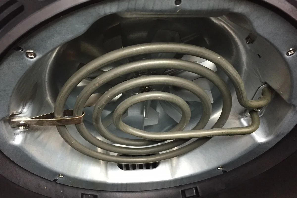 The interior of an air fryer showing the coiled heating element and the fan blades behind it.