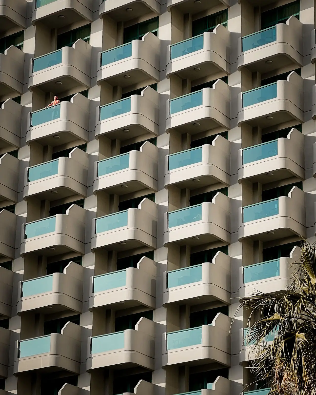 Curved balconies with glass railings repeating up the face of a modern high-rise apartment building in Dubai.