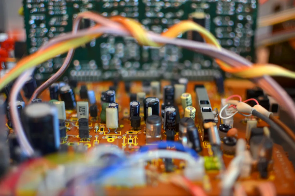 Rows of capacitors and coloured ribbon wiring on a densely populated circuit board inside an opened machine.