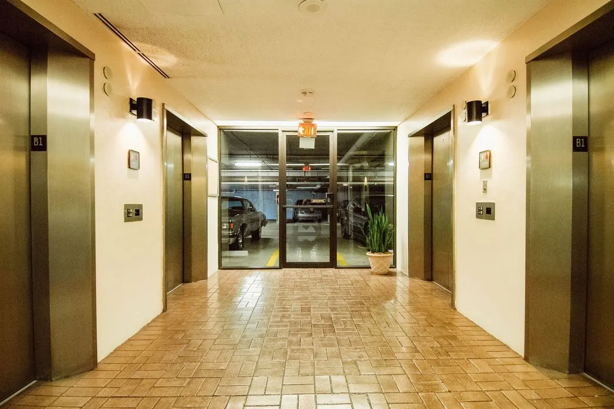 A basement lift lobby marked B1 with lifts on both sides and a glazed door opening onto a parking level.
