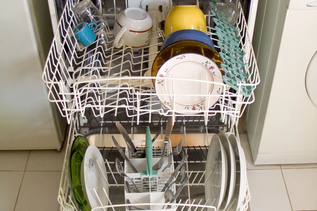 An open built-in kitchen dishwasher beside cabinetry during an appliance removal assessment in an apartment