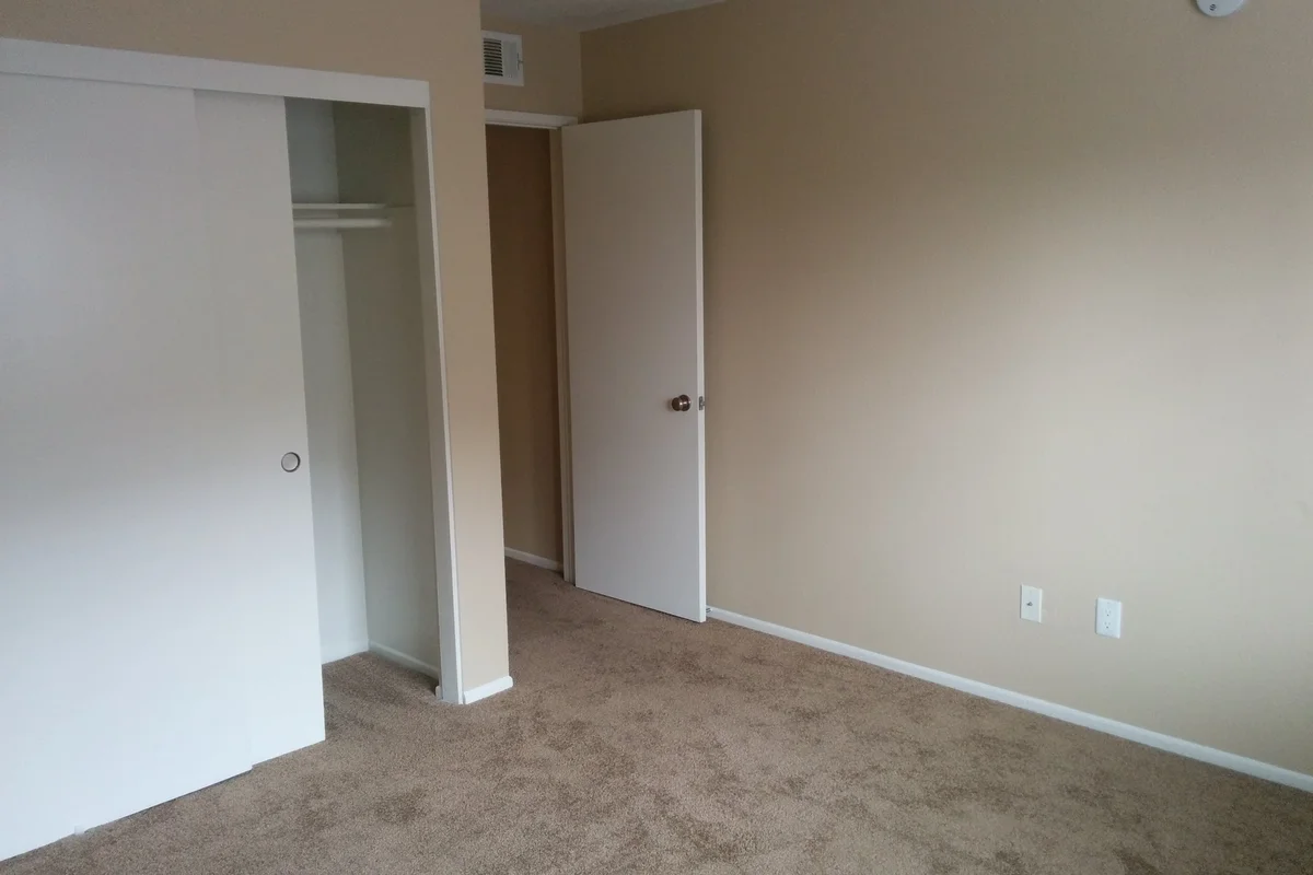Empty apartment bedroom with clean carpet and fitted sliding wardrobes ready for move-out deep cleaning.