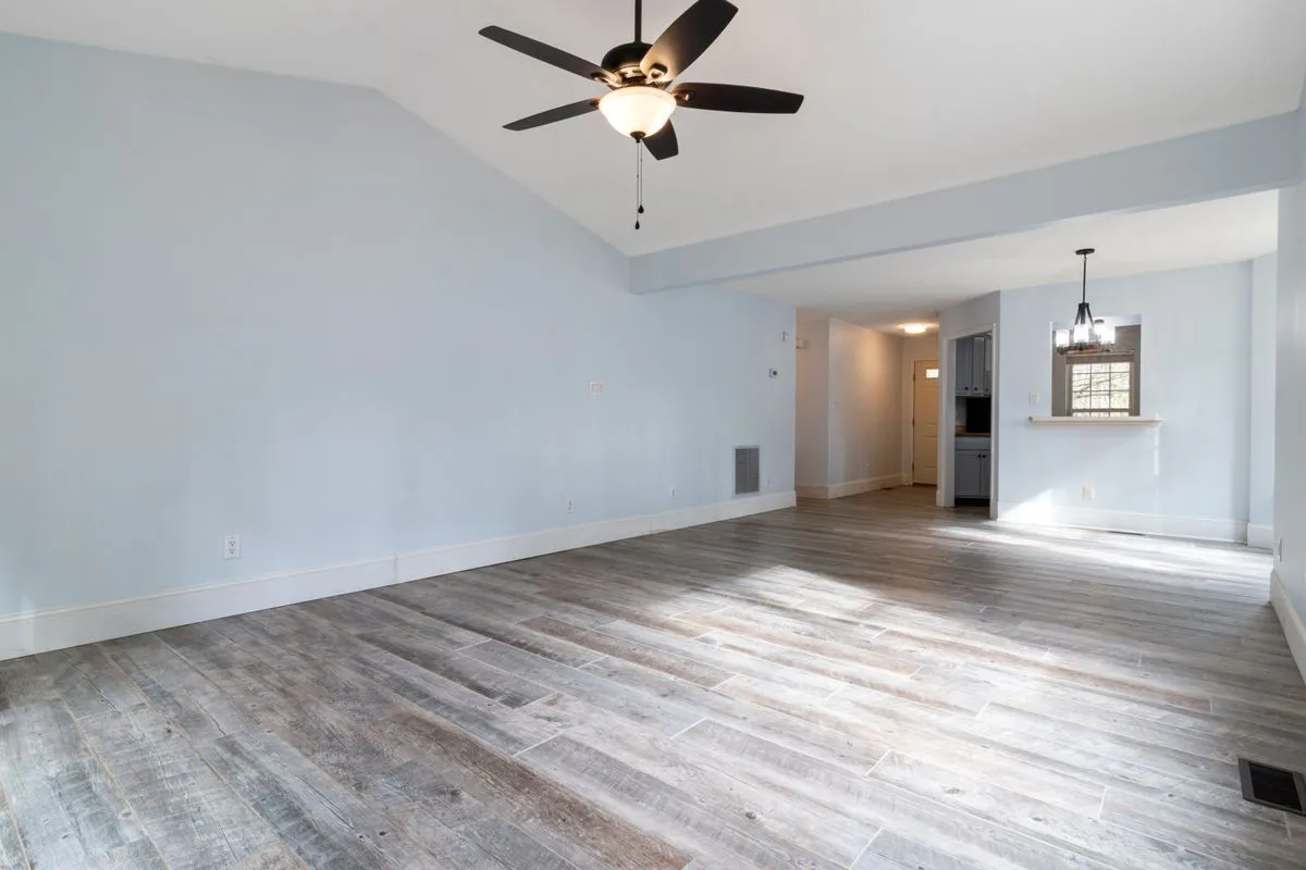 An empty living room with wooden flooring after the furniture has been removed.