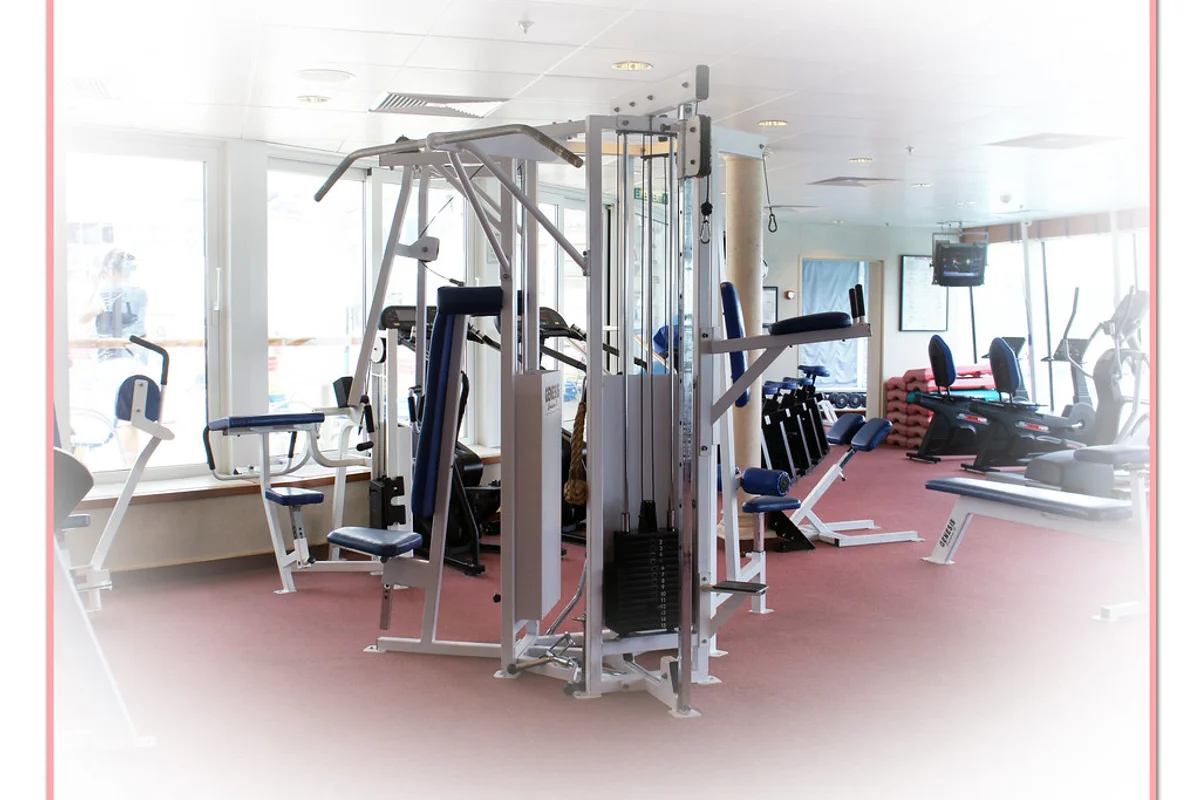 Heavy selectorized weight machines and dumbbell racks arranged over high-density commercial rubber gym flooring