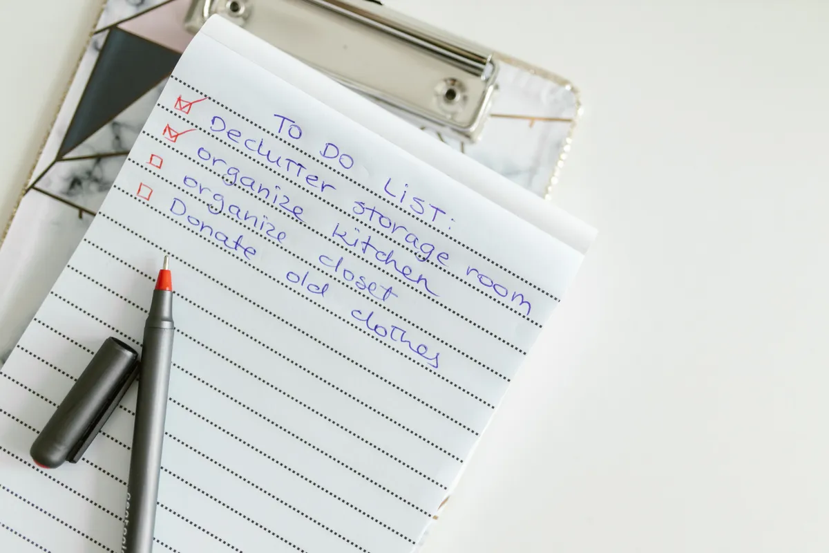 A handwritten to-do list on a clipboard, with two boxes checked and two still empty.