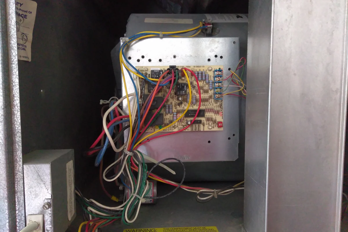 Technician inspecting complex electrical control wiring and compressor housing during appliance depollution