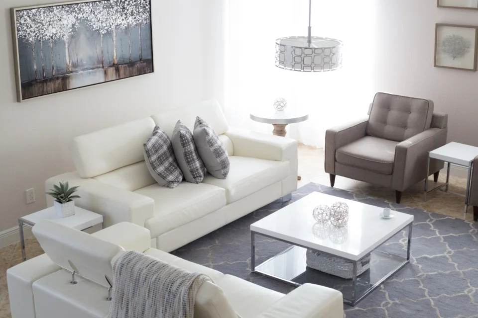 A spacious villa living room with a large white sofa, armchairs, a coffee table and side tables that would not fit a smaller apartment.