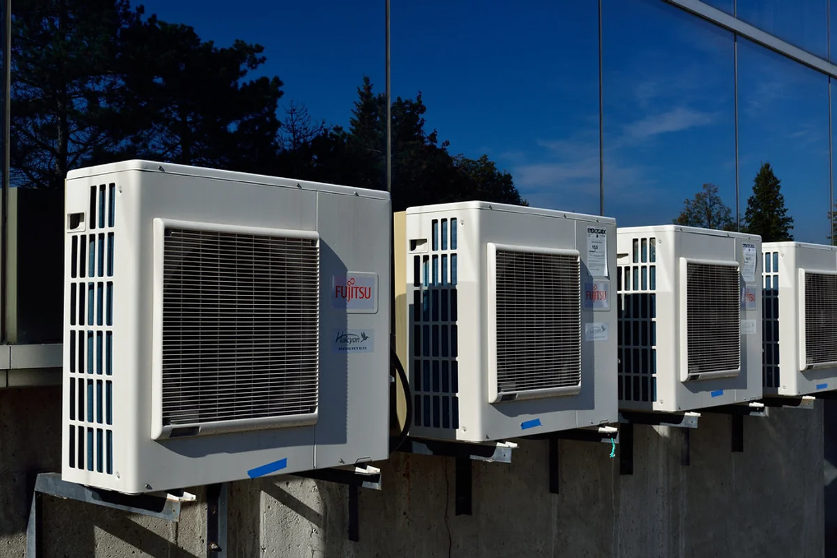 Row of outdoor air conditioner compressor units mounted on external wall brackets.