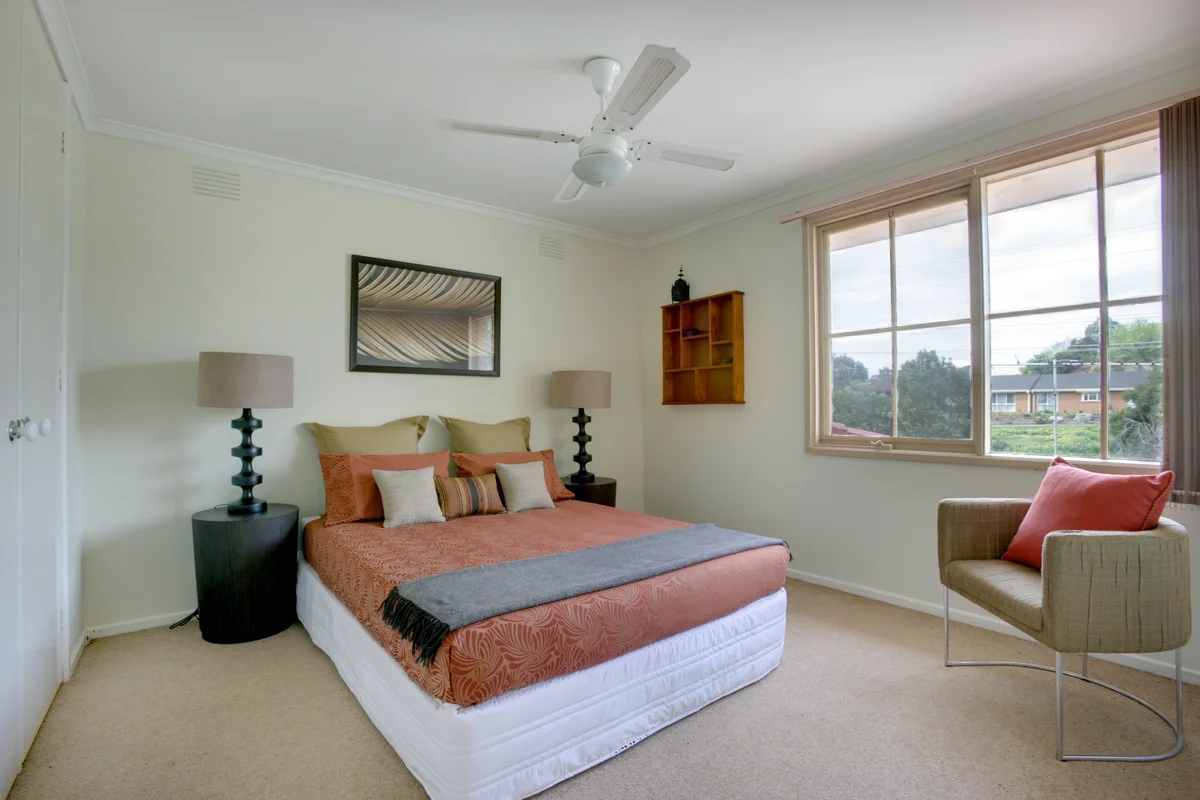 A tidy bedroom with a made bed, a bedside table and a lamp, left exactly as it was before an estate clearance.