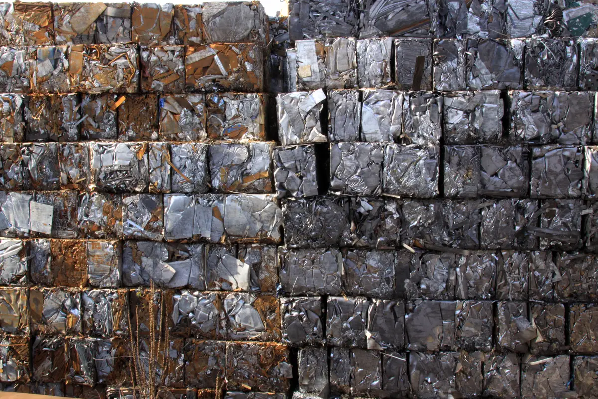 A wall of stacked bales of compressed scrap metal, with rusty bales on the left and darker, cleaner ones on the right.