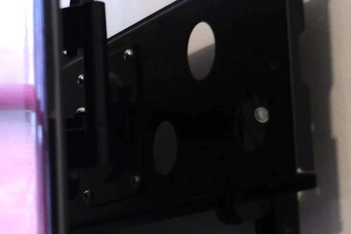 Close-up of a black full-motion television wall-mount bracket and articulating arm fixed to a wall.