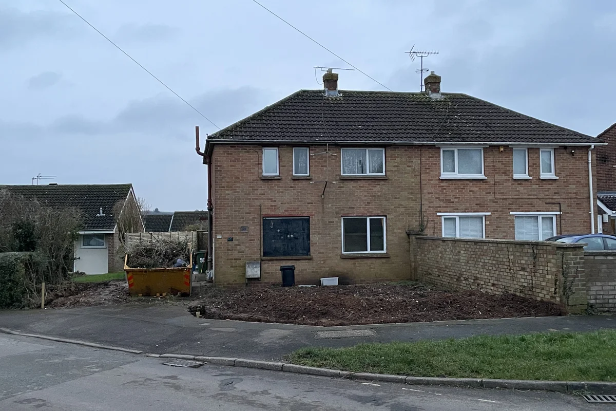 Active residential clearance operation with workers carrying dismantled furniture components and items during an urgent property clearout.