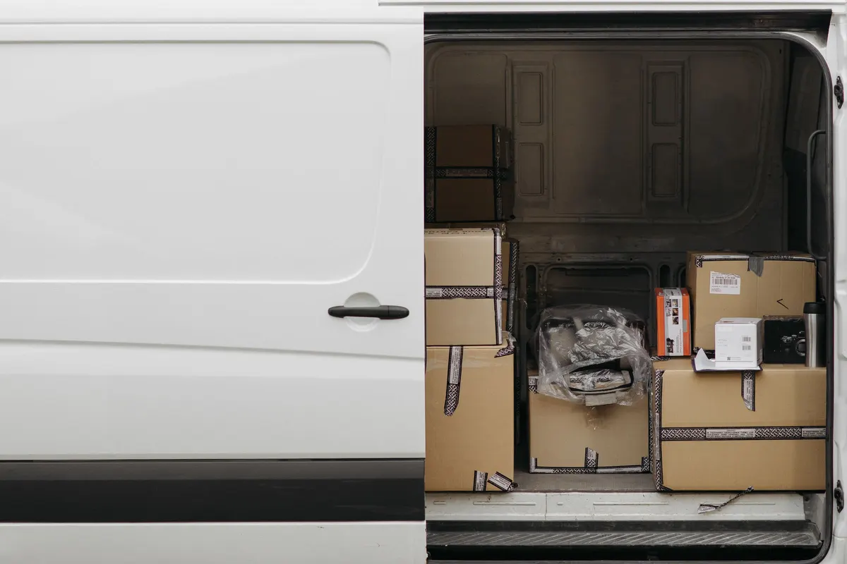 The open side door of a white van showing boxes stacked part-way up the cargo space.