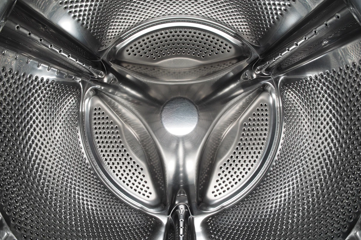 Close-up of a stainless steel washing machine drum and internal baffles representing salvageable spare parts